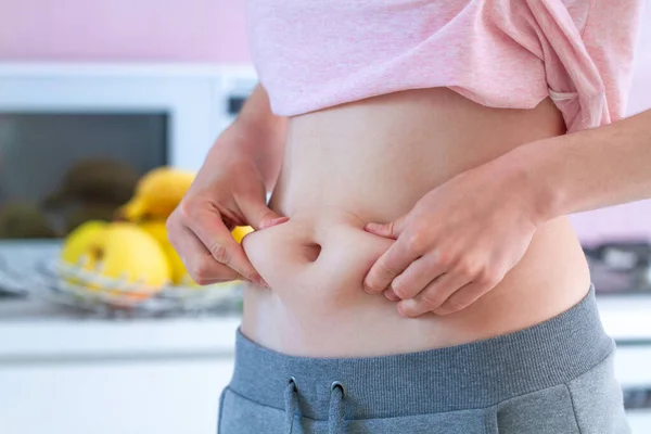 女人在腰部挤压多余的脂肪 并且因为不活跃的生活方式和垃圾不健康的食物而增加了额外的体重 超重的概念 — 图库照片