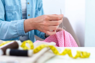 Dikiş işlemi. Ev hanımı evde iğne ve çeşitli dikiş malzemeleri kullanarak dikiş dikiyor. 