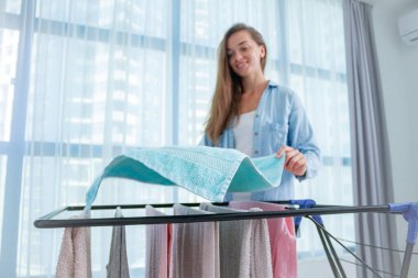 Çamaşırcı kadın evde çamaşır yıkadıktan sonra ıslak çamaşırları kurutucuya asar. Ev işleri ve ev işleri. 