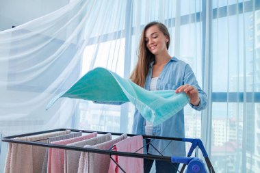 Mutlu ev hanımı evdeki çamaşırlardan sonra çamaşır kurutma makinesine ıslak çarşaf asar. Ev işleri ve ev işleri. 