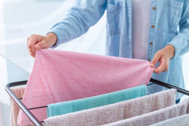 Ev hanımı ıslak çamaşırları kurutucuya asar.