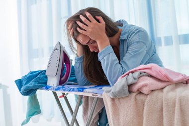 Çamaşırları evde ütülemekten yorgun düşmüş bir kadın..