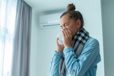 Üzgün kadın klimadan üşütüp hapşırmış. 