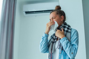 Sneezing woman caught a cold from the air conditioner at home  clipart