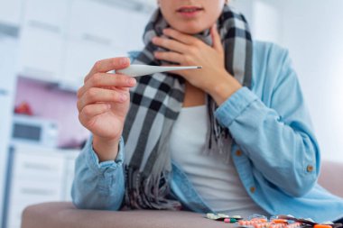 Hasta kadın grip sırasında boğaz ağrısı ve yüksek ateşten muzdarip. Evde soğuk muamele