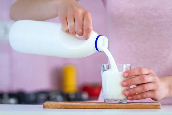 女性はガラスの近くに新鮮な牛乳を注いでいます 乳製品 — ストック写真