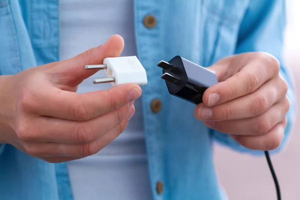 Adaptör ve telefon şarj cihazı kullanan kişi.