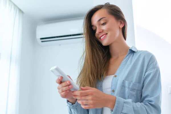 Jovem Feliz Mulher Sorriso Ajusta Temperatura Condicionado Usando Controle Remoto — Fotografia de Stock