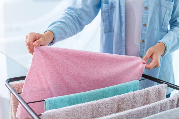 Ev hanımı ıslak çamaşırları kurutucuya asar.