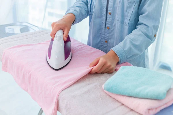 Ironing of linen and clothes after laundry on ironing board at home