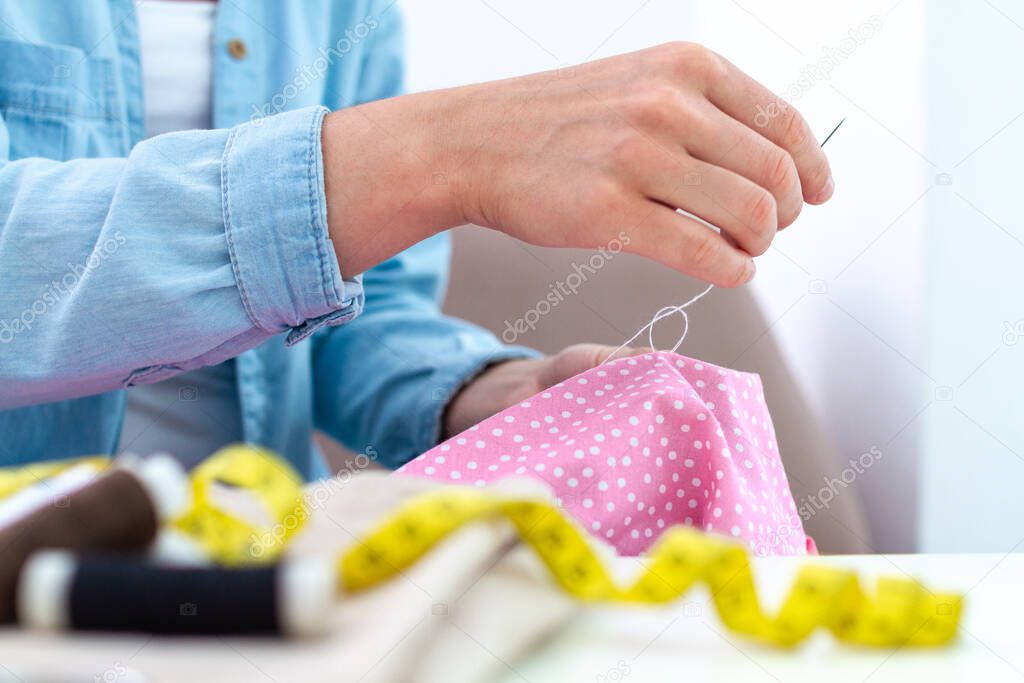 Sewing process. Housewife patches clothes and sews at home using needle and various sewing supplies 