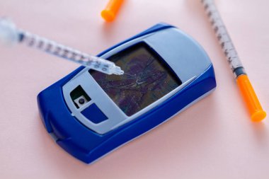 Şeker hastası kan şekeri ölçerini insülin enjeksiyonu için bir şırıngayla kırıyor. Şeker hastalığını durdur. Kronik hastalıkla savaş 