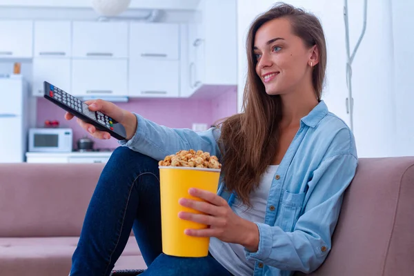 幸せな笑顔女性Restingオンソファと食べるカリカリポップコーンの間に見ますテレビ ホーム — ストック写真
