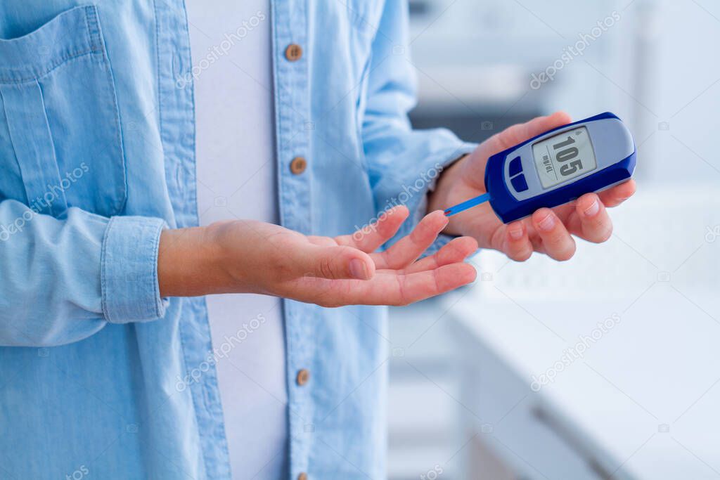 A diabetic patient measures blood glucose with a glucose meter at home. Diabetes woman control and analyze glucose level blood 