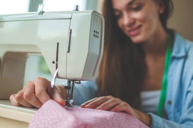 Dikiş makinesi kullanan terzi kadın ve dikiş dikmek için farklı aksesuarlar. 