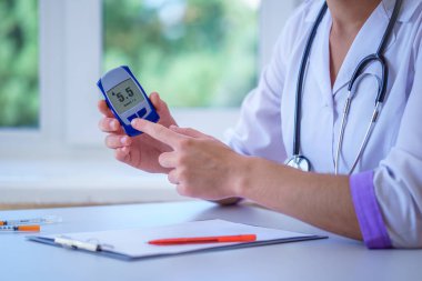 Doktor, hastane muayenesi ve muayenesi sırasında kan şekeri seviyesinde şeker hastasına glikoz ölçer gösteriyor. Diyabet yaşam tarzı ve sağlık hizmetleri