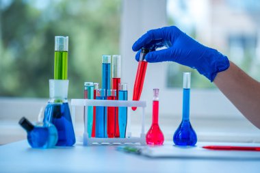 Laboratuvar asistanı klinik laboratuvar araştırması yapıyor. Elinde kırmızı sıvı test tüpü tutuyor. İlaç, eczane ve kozmetoloji kavramı. 