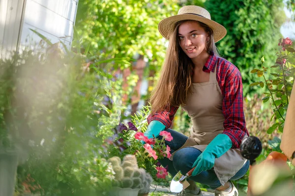 エプロンの庭師の女性の肖像自宅の庭の花壇にペチュニアの花 園芸と花栽培 フラワーケア — ストック写真