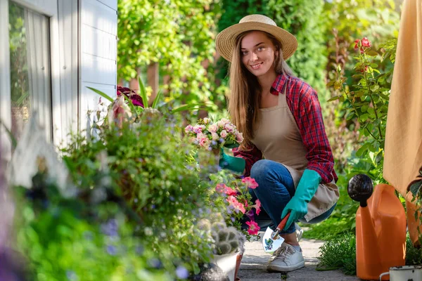 ホームガーデンの花壇に手袋 エプロン植物ペチュニア花の幸せな園芸女性の肖像画 園芸と花栽培 フラワーケア — ストック写真