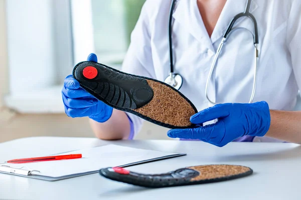 Nurse holds orthopedic insoles for the treatment and prevention of flat feet. Foot care and wearing comfortable shoes