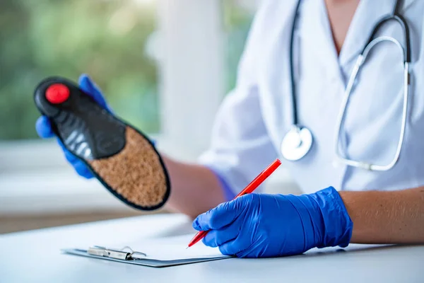 Doctor write out a medical prescription for orthopedic insoles for the treatment and prevention of flat feet. Foot care and wearing comfortable shoes