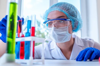 Kadın kimyager test için çeşitli bilimsel cam ve tüplerle klinik laboratuvar araştırmaları yapıyor. İlaç, eczane ve kozmetoloji kavramı. 