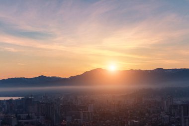 Dağlarda büyüleyici bir gün doğumu ve sabahın erken saatlerinde sisli bir şehirde..
