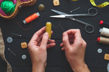 Koyu ahşap arka planda dikiş seti. Üst Manzara. Bir terzinin elinde iplik makarası