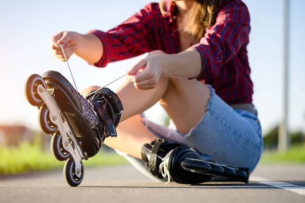 Woman laces roller skating for inline skating. Teenager rollerblading outdoors.