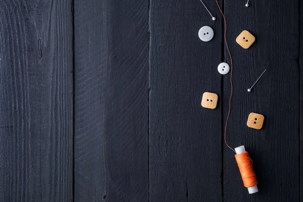 Bobina Arancione Filo Spilli Bottoni Cucire Uno Sfondo Nero Legno — Foto Stock