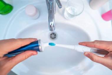 İnsan dişlerini ultrasonik diş fırçasıyla fırçalar ve diş fırçası olarak diş ürünleri kullanır ve evde banyoda temiz hava almak için. Ağız temizliği, diş ve diş sağlığı, sağlıklı dişler. Günlük yaşam ve rutinler 