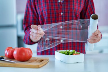 Using food polyethylene plastic film for food storage in fridge at home 