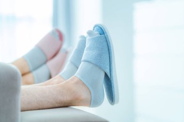 Aile çifti evdeki kanepede birlikte dinleniyor. Rahat, rahat terlikler.