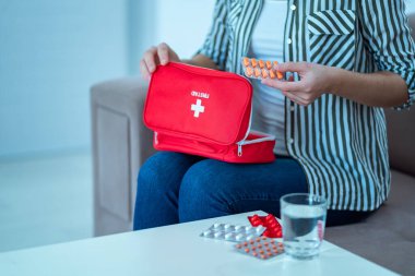 Woman holds a medical kit with medicine at home. First aid for pain and illness