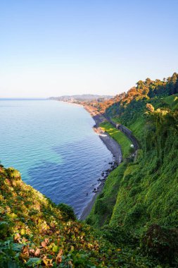 Beautiful, bewitching view of the blue sea, green cape and the railway from the botanical garden in Batumi Georgia in clear sunny day