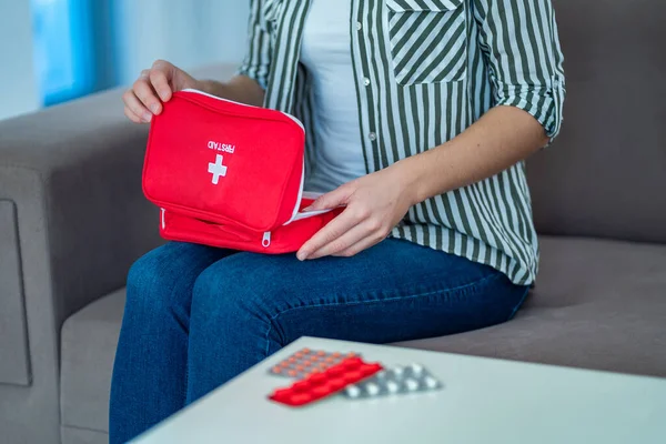 A woman holds a medical first aid kit with medicine at home