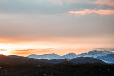 Dawn landscape on a background of snowy mountains in the fog early in the morning