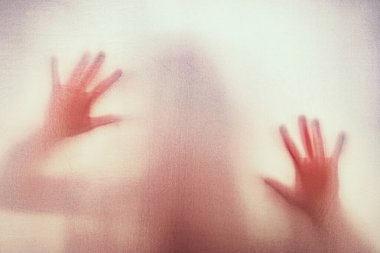 Mat kırmızı camın arkasındaki korkunç paranormal hayalet korku kadının gölgesi. Bulanık el ve vücut şekli soyutlaması.