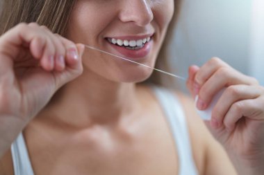 Mutlu sağlıklı kadın diş fırçası ve diş temizliği için diş ipi kullanıyor. Diş bakımı