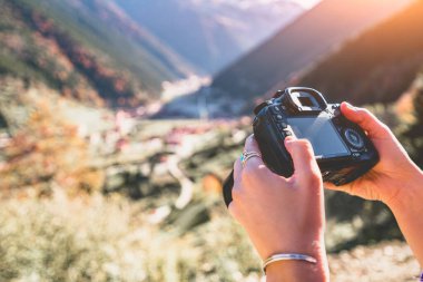 Person taking pictures of the mountains landscape using photo camera during travel