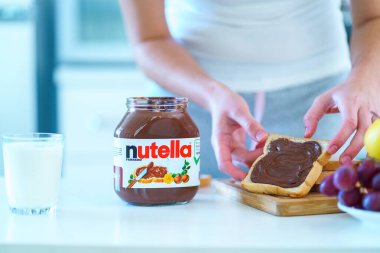 Batumi, Georgia - 11 Kasım 2019. Kadınlar sağlıklı bir kahvaltı için tost ekmeğine çikolata fındıklı tereyağı sürer.. 