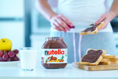 Batumi, Georgia - 11 Kasım 2019. Kadın tatlı olarak tost ekmeğine çikolata fındıklı krema sürüyor. 