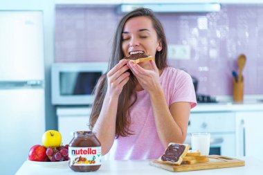 Batumi, Georgia - 11 Kasım 2019. Neşeli yemek yiyen kadın evde tatlı yerken çikolatalı sandviç yiyor.