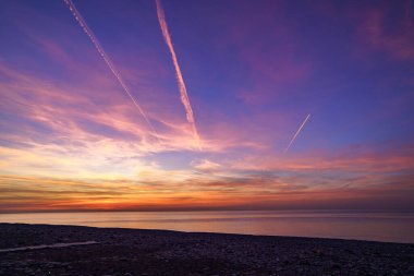 Gün batımından sonra denizdeki uçak izleri ile büyüleyen gökyüzü. 