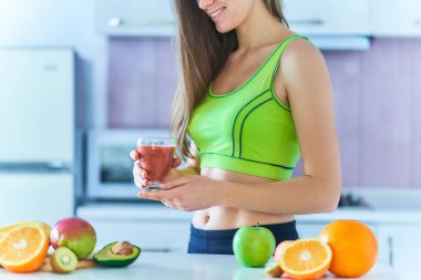 Spor giyim diyetindeki kadın kilo vermek için taze meyve suyu içiyor. Sağlıklı beslenmek için vitamin içecekleri      
