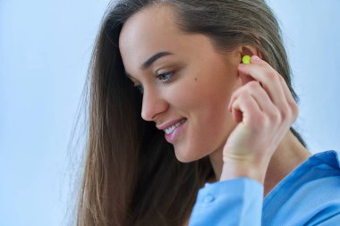 Kulak tıkacı kullanan hoş bir esmer kadın. Daha iyi uyumak için gürültü koruması 