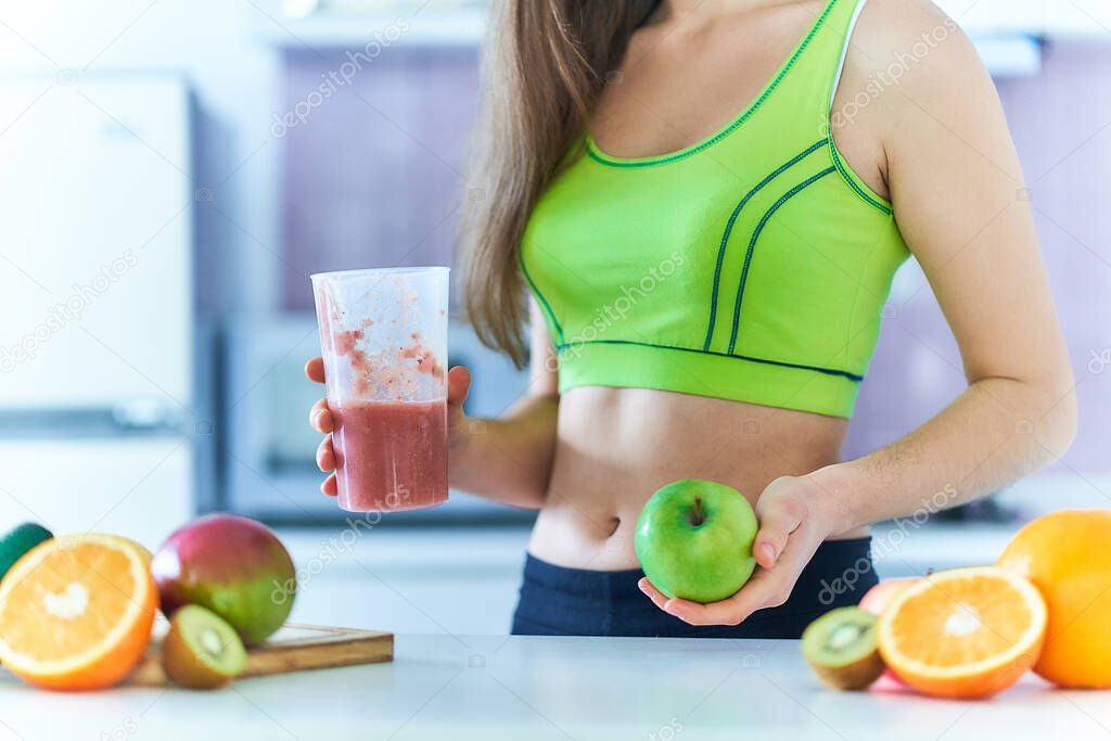 Fit woman in sportswear drinks a fresh fruit smoothie for losing weight. Vitamin diet drinks for healthy eating      