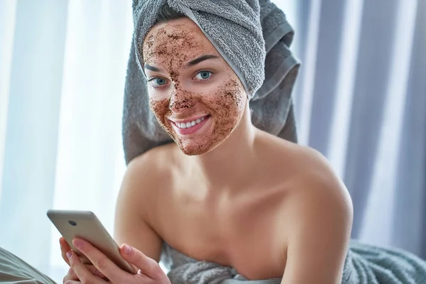 Portrait of smiling happy woman in bath towel with natural face coffee scrub after shower during spa day and skin care routine indoors