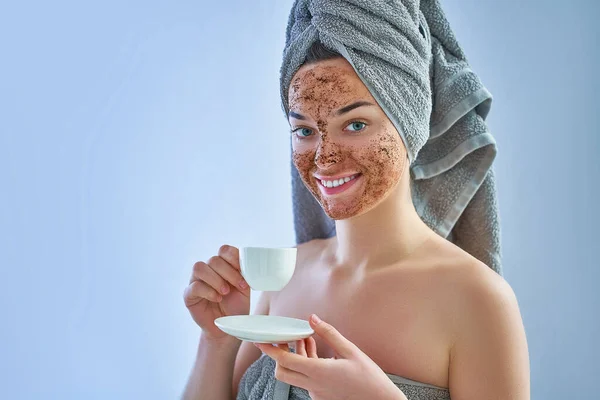 Portrait of smiling woman in bath towel with natural face coffee scrub mask after shower during spa day and skin care routine at home