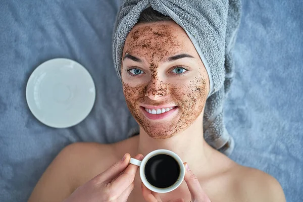 Portrait of smiling healthy happy woman with coffee scrub facial mask during spa day and skin care routine at home